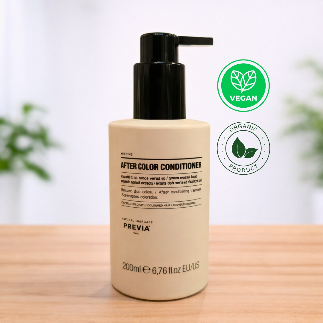 Frasco de Previa After Color Condicionador com doseador preto, posicionado sobre uma base de madeira. O rótulo indica tratar-se de um condicionador pós cor de 200ml, formulado especificamente para cabelos pintados com extratos de damasco orgânico. No canto superior direito, destacam-se os selos circulares "Vegan" e "Organic Product". O design é minimalista e elegante, refletindo a linha de cuidados naturais da Previa Italia.