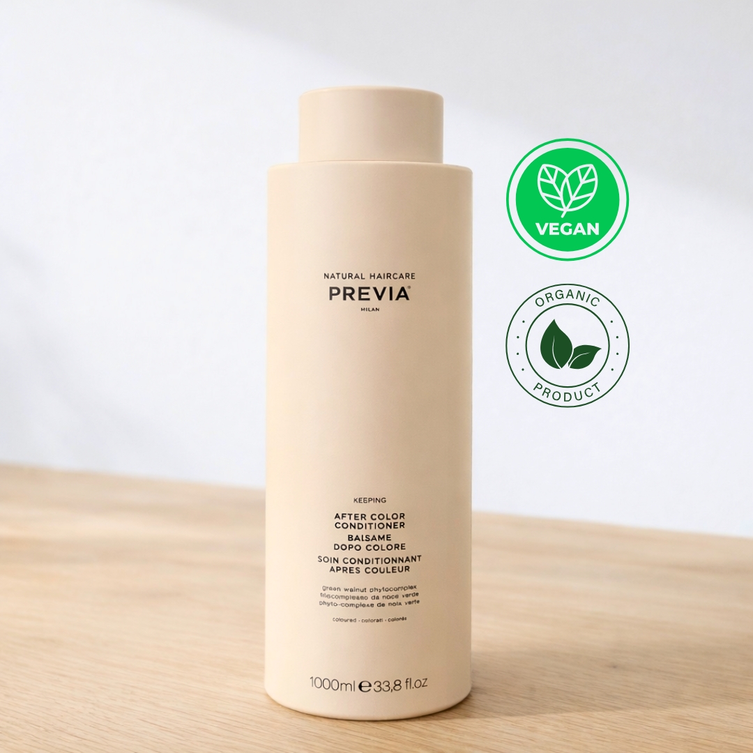 Frasco de Previa After Color Condicionador com doseador preto, posicionado sobre uma base de madeira. O rótulo indica tratar-se de um condicionador pós cor de 200ml, formulado especificamente para cabelos pintados com extratos de damasco orgânico. No canto superior direito, destacam-se os selos circulares "Vegan" e "Organic Product". O design é minimalista e elegante, refletindo a linha de cuidados naturais da Previa Italia.